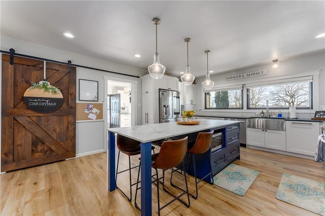 kitchen with white cabinetry, light wood-style floors, appliances with stainless steel finishes, and a sink