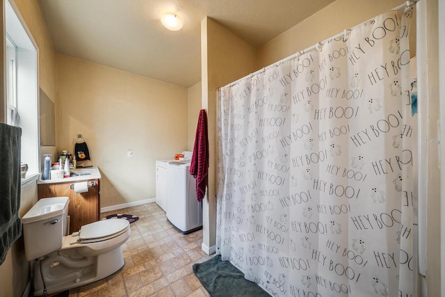 bathroom featuring toilet, stone finish floor, curtained shower, washer / clothes dryer, and baseboards