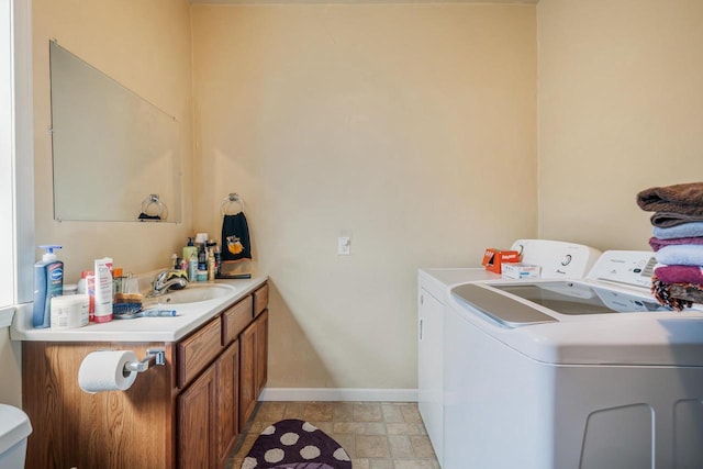 laundry room with laundry area, washing machine and dryer, baseboards, and a sink