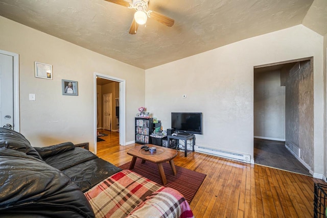 living room featuring wood-type flooring, a ceiling fan, baseboards, and baseboard heating