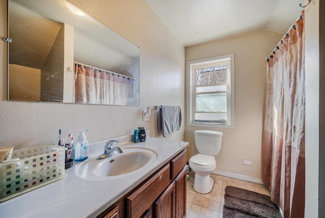 bathroom featuring stone finish flooring, baseboards, toilet, lofted ceiling, and vanity