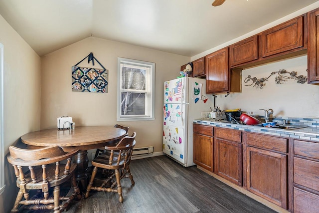 kitchen featuring brown cabinets, a sink, dark wood-style floors, tile countertops, and vaulted ceiling