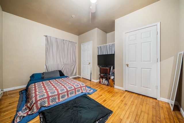 bedroom with a ceiling fan, baseboards, and wood-type flooring