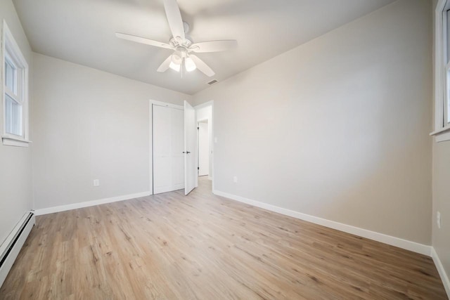 unfurnished room featuring ceiling fan, light wood-style floors, baseboards, and a baseboard radiator