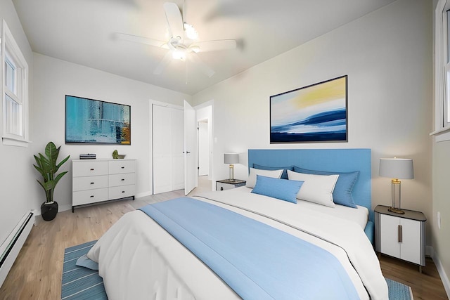 bedroom featuring a baseboard heating unit, baseboards, wood finished floors, and a ceiling fan