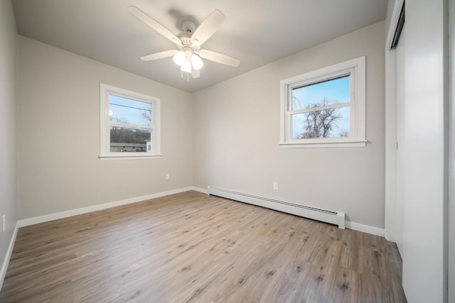 empty room with a baseboard heating unit, wood finished floors, baseboards, and ceiling fan