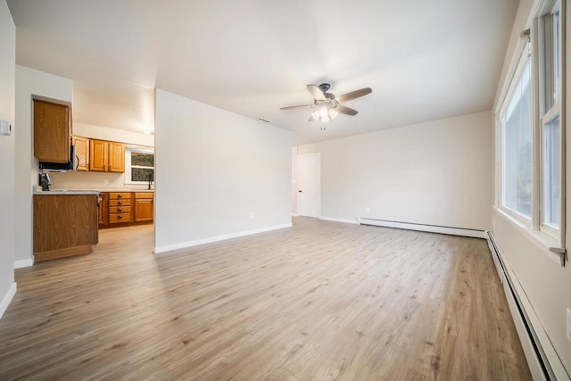 unfurnished living room featuring ceiling fan, a baseboard radiator, baseboards, and light wood-style flooring