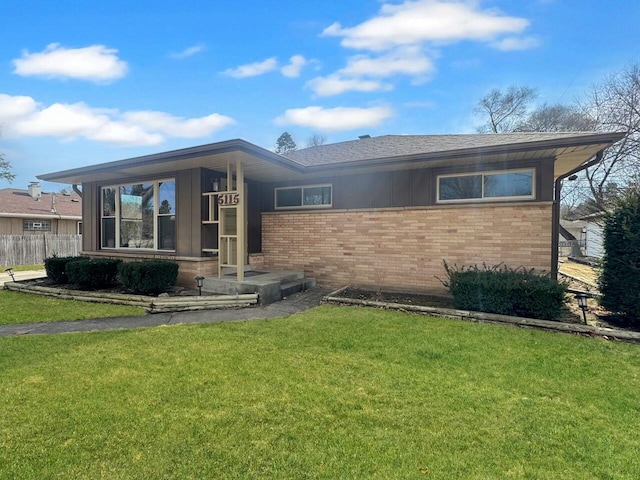 view of front facade with a front lawn, fence, and brick siding