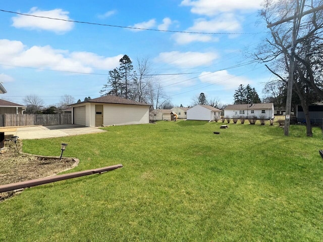 view of yard with concrete driveway, fence, an outbuilding, and a garage