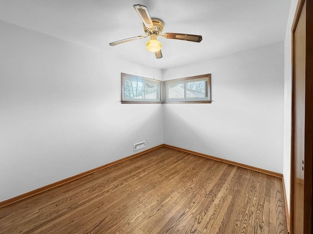 empty room featuring a ceiling fan, wood finished floors, and baseboards