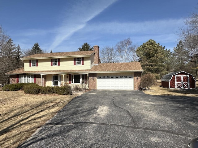 view of front of house with aphalt driveway, a porch, a chimney, a garage, and a storage unit