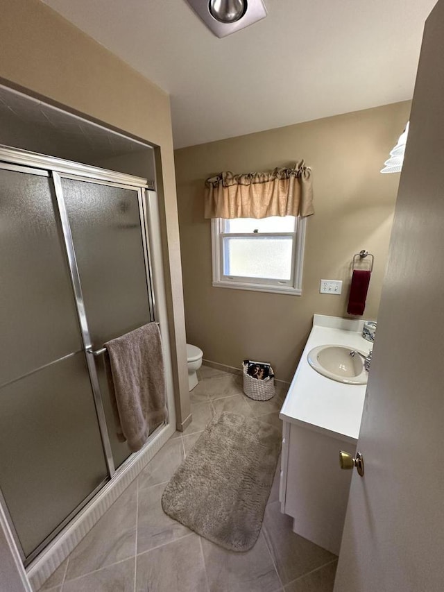 bathroom featuring baseboards, toilet, a stall shower, tile patterned floors, and vanity