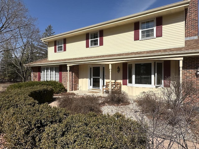 view of front of home with a porch and brick siding