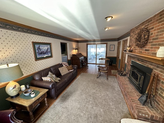 living area featuring wallpapered walls, crown molding, a brick fireplace, and wood finished floors