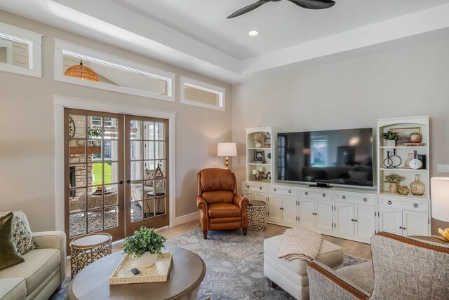 living room featuring baseboards, french doors, light wood-type flooring, and ceiling fan