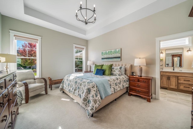 bedroom with light carpet, a notable chandelier, connected bathroom, and a raised ceiling