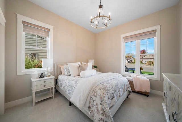 bedroom with light colored carpet, baseboards, and an inviting chandelier