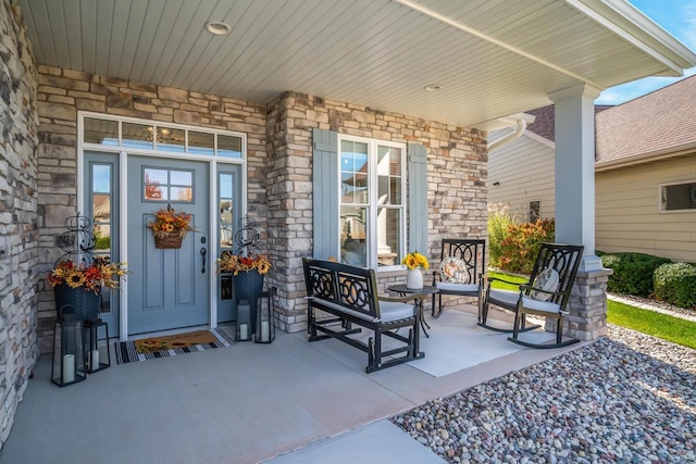 view of exterior entry featuring stone siding and covered porch