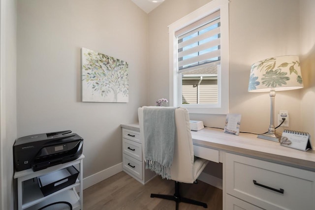 office space featuring light wood-style floors, baseboards, and built in desk