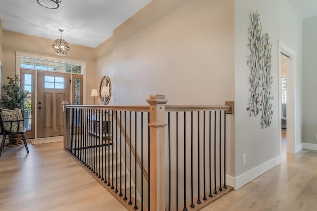 foyer entrance with a notable chandelier, baseboards, and wood finished floors