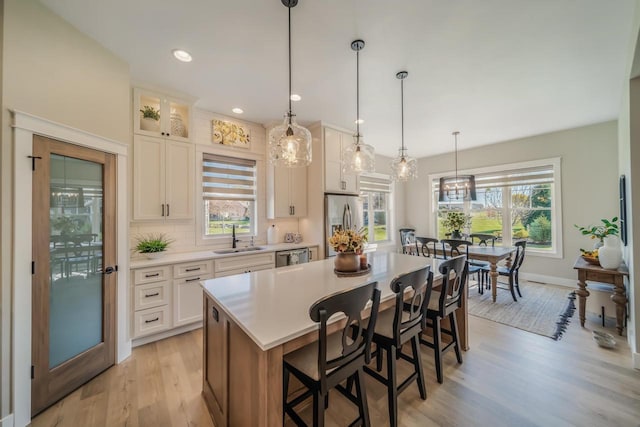 kitchen featuring a breakfast bar, a sink, a center island, appliances with stainless steel finishes, and light countertops