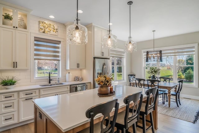 kitchen with backsplash, light countertops, appliances with stainless steel finishes, plenty of natural light, and a sink