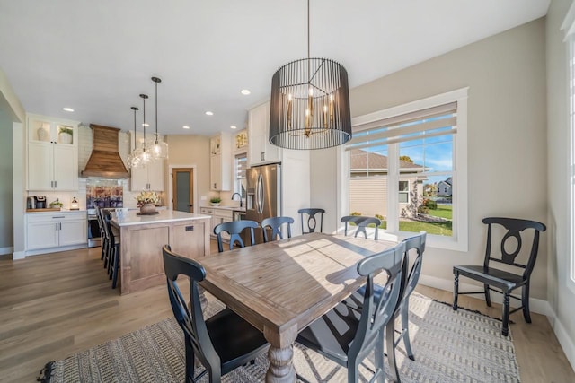 dining area with a notable chandelier, baseboards, and light wood-style floors