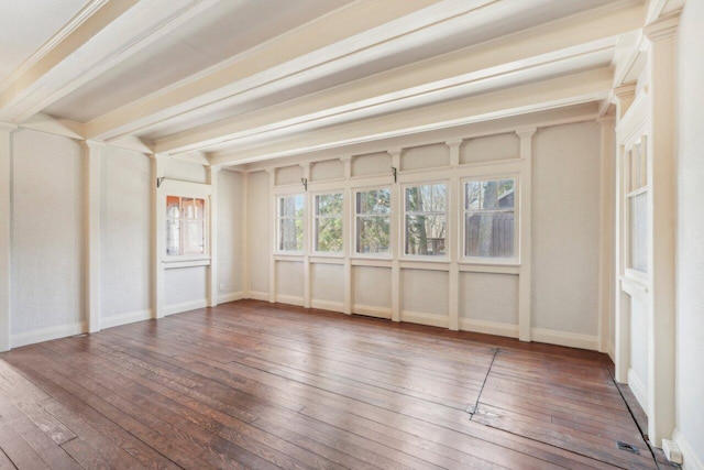 empty room featuring beamed ceiling, baseboards, and hardwood / wood-style floors