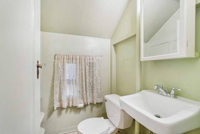 bathroom with toilet, lofted ceiling, and a sink