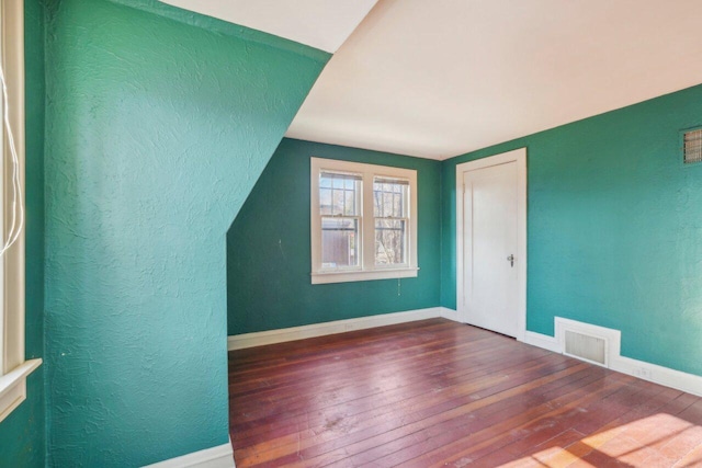 bonus room with a textured wall, visible vents, baseboards, and hardwood / wood-style flooring