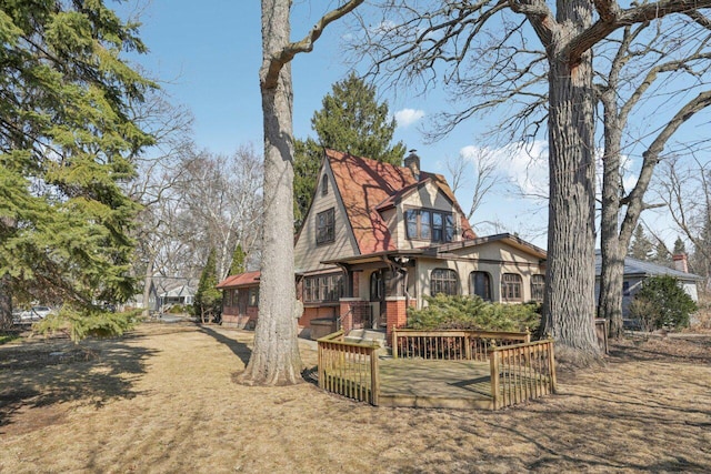 back of property featuring brick siding, a wooden deck, and a chimney