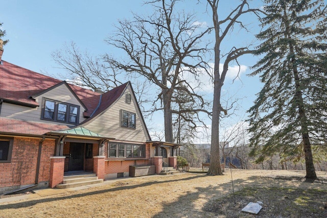 view of side of home featuring a standing seam roof, brick siding, and metal roof