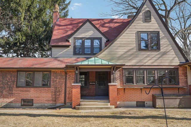 view of front of home with metal roof, brick siding, a chimney, and a standing seam roof