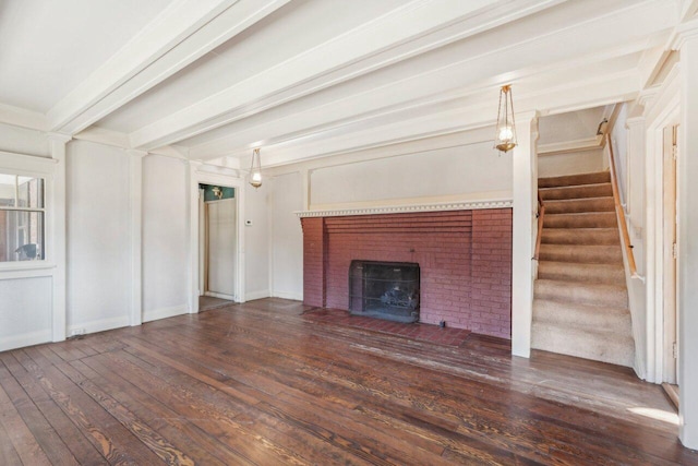 unfurnished living room featuring hardwood / wood-style floors, a brick fireplace, stairway, and beamed ceiling