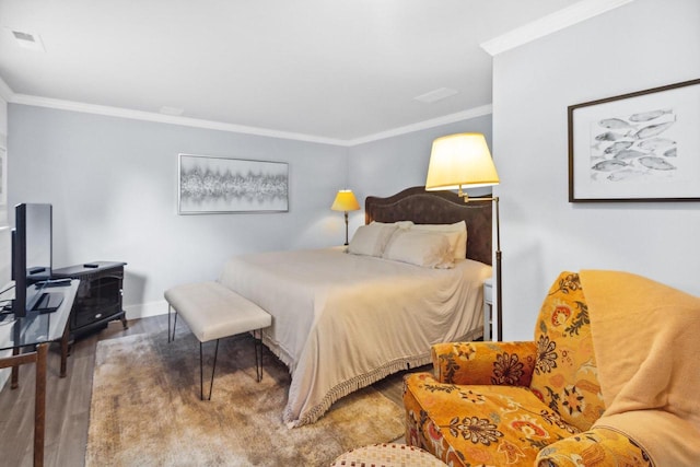 bedroom featuring baseboards, wood finished floors, visible vents, and ornamental molding