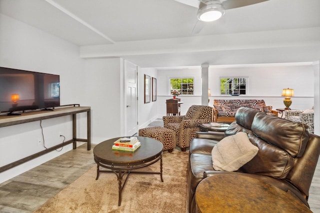 living area featuring ornate columns, baseboards, ceiling fan, and wood finished floors