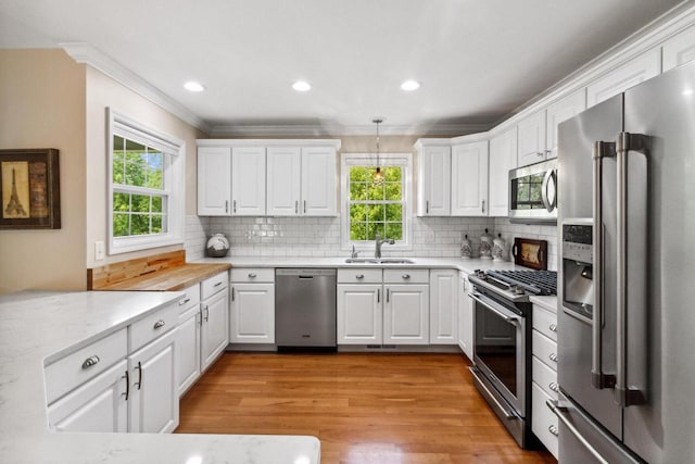 kitchen featuring a sink, stainless steel appliances, a wealth of natural light, and white cabinets