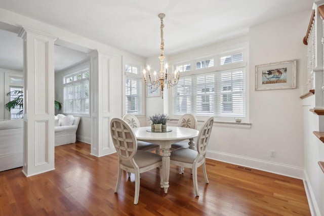 dining room with a chandelier, baseboards, visible vents, and wood finished floors