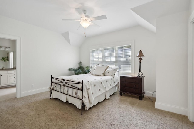 bedroom featuring baseboards, vaulted ceiling, light carpet, ensuite bath, and a ceiling fan