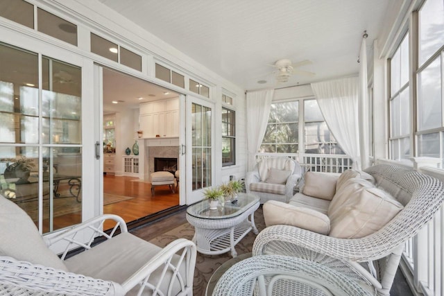 sunroom with a fireplace and ceiling fan