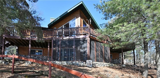 rear view of house featuring a wooden deck and a sunroom