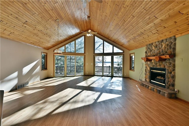 unfurnished living room with visible vents, high vaulted ceiling, a ceiling fan, wood finished floors, and a stone fireplace