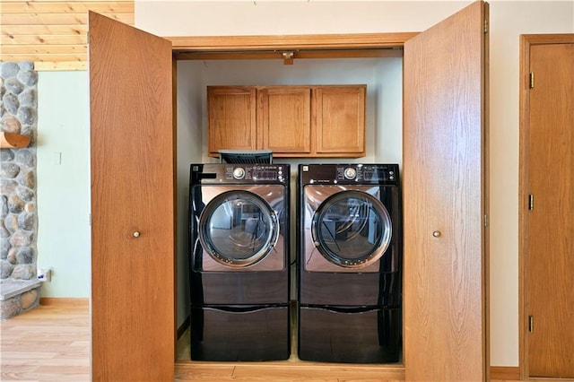 clothes washing area with cabinet space, independent washer and dryer, baseboards, and wood finished floors