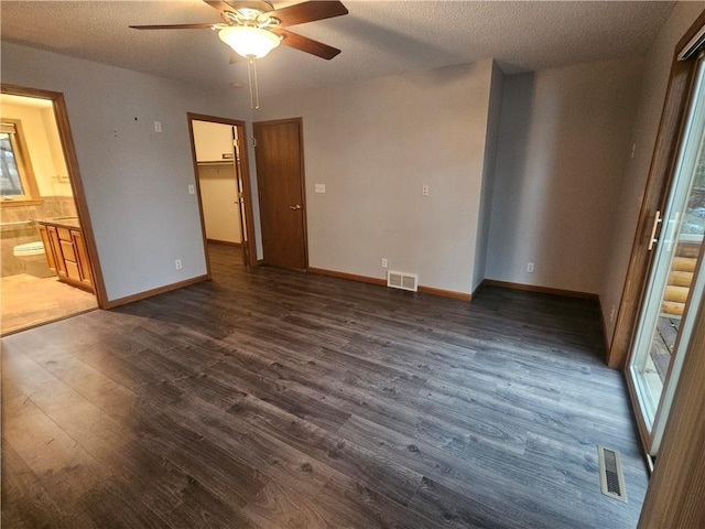 unfurnished bedroom featuring visible vents, connected bathroom, a textured ceiling, and dark wood-type flooring