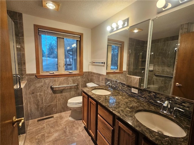 bathroom featuring a textured ceiling, a shower stall, toilet, and a sink