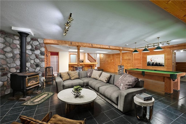 tiled living area featuring billiards, a textured ceiling, stairs, wooden walls, and a wood stove