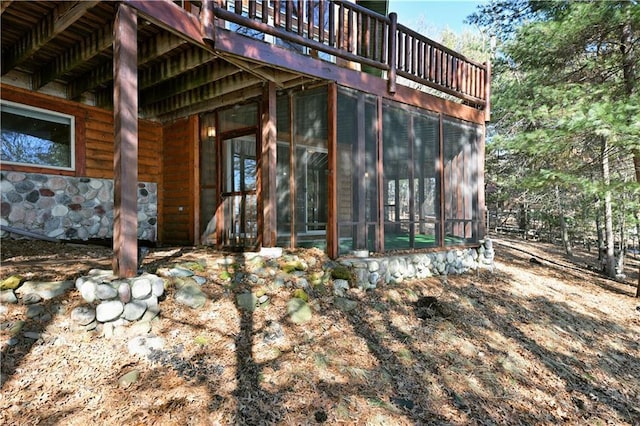 exterior space featuring stone siding and a sunroom