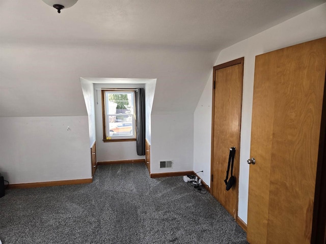 additional living space featuring lofted ceiling, baseboards, visible vents, and dark carpet