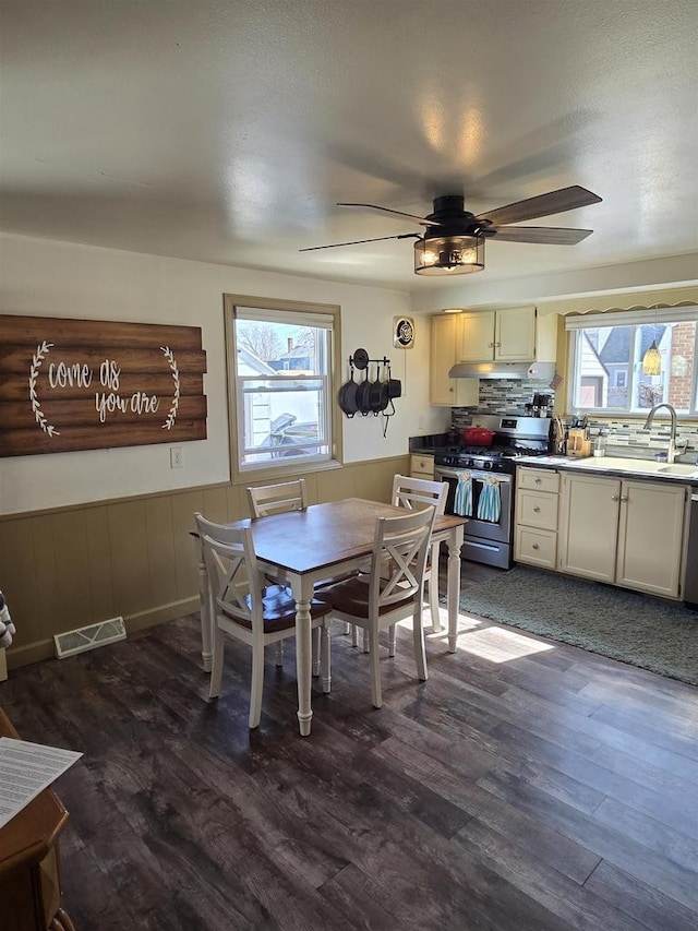 dining area featuring ceiling fan, a healthy amount of sunlight, visible vents, and wainscoting