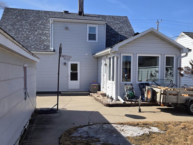 rear view of house with a shingled roof, a patio, and fence